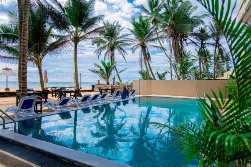 una piscina con sedie e palme di Nico Beach Hotel a Hikkaduwa