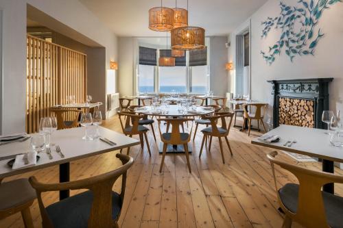 a restaurant with tables and chairs and a large window at Housel Bay Hotel in Lizard