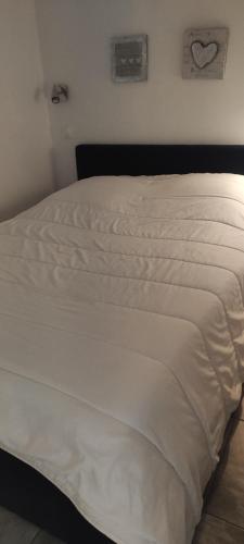 a white bed in a bedroom with a heart on the wall at 2 pièces avec grande terrasse in La Ciotat