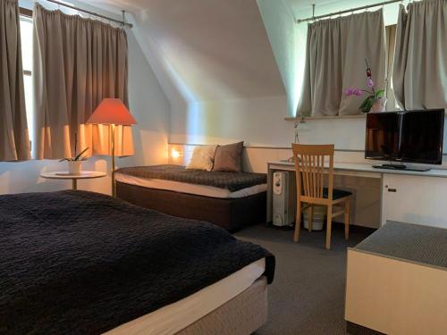 Habitación de hotel con 2 camas y escritorio con TV. en Hotel Blaufuchs en Petershagen