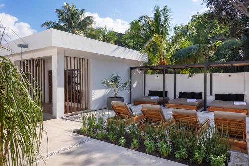 a patio with chairs and tables and palm trees at Illa Cozumel in Cozumel