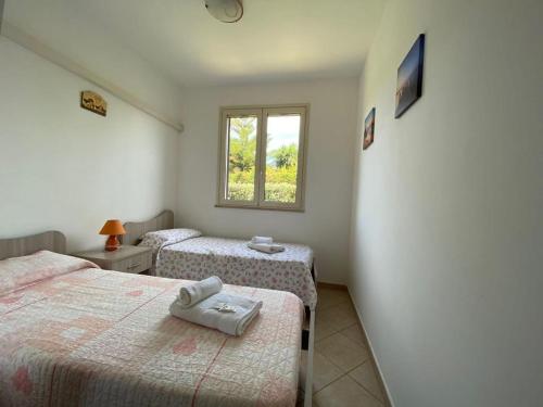 a bedroom with two beds and a window at Case Vacanze Paradise Beach Vicino Cefalù PISCINA APERTA in Campofelice di Roccella