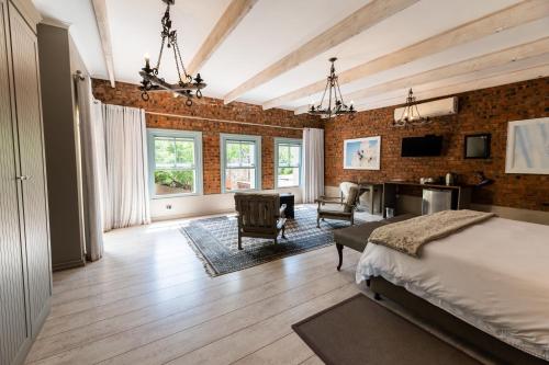 een slaapkamer met een bakstenen muur, een bed en een bureau bij Migdash Guesthouse in Hartbeespoort