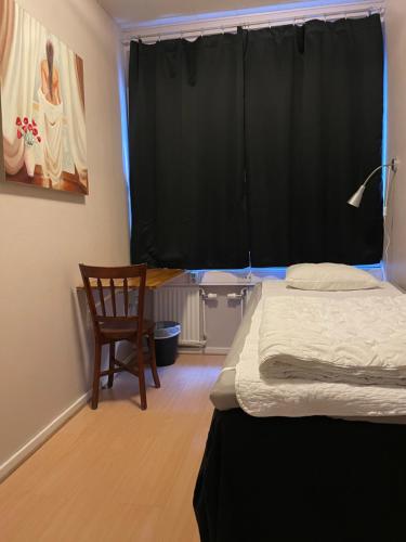 a bedroom with a bed and a chair and a window at Uppsala City Hostel in Uppsala