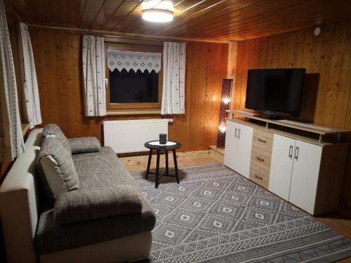 een woonkamer met een bank en een flatscreen-tv bij Erwin's in Bildstein
