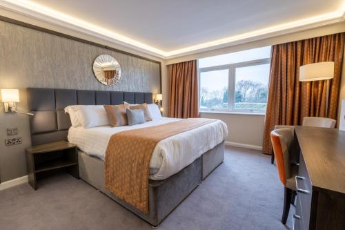 a hotel room with a large bed and a desk at Park Hall Hotel and Spa Wolverhampton in Wolverhampton