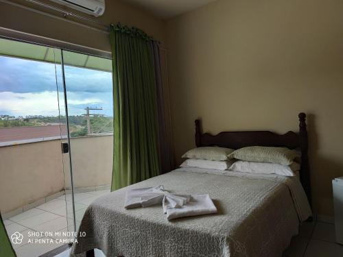 a bedroom with a bed and a window with green curtains at Canastra Season in São Roque de Minas