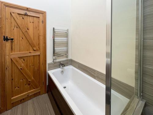 a bath tub in a bathroom with a wooden door at The Bobbin in Ashover