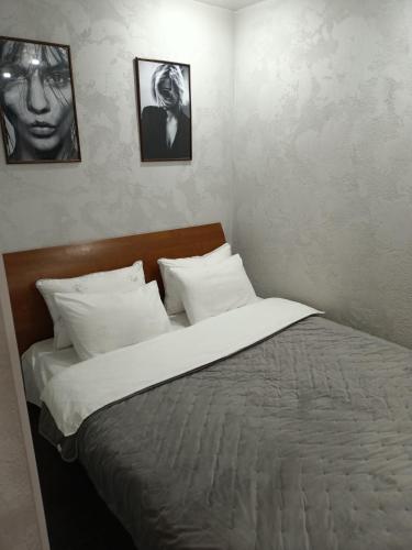 łóżko w sypialni z dwoma zdjęciami na ścianie w obiekcie Уютная и просторная квартира в 50 метрах от городского парка w mieście Pietropawłowsk Kamczacki