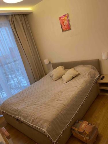 a bed with two pillows in a bedroom with a window at Przytulny apartament na zamkniętym osiedlu in Kąty Rybackie