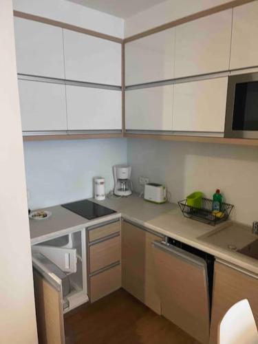 uma cozinha com armários brancos e uma bancada em Przytulny apartament na zamkniętym osiedlu em Kąty Rybackie
