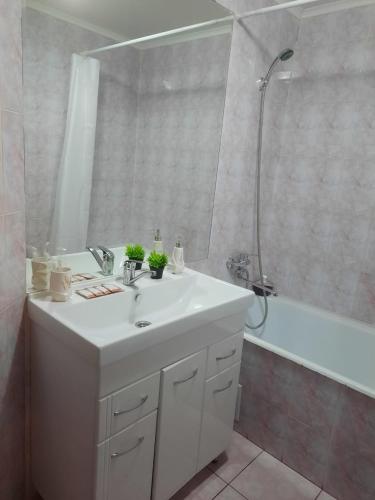 W łazience znajduje się biała umywalka i prysznic. w obiekcie Уютная и просторная квартира в 50 метрах от городского парка w mieście Pietropawłowsk Kamczacki