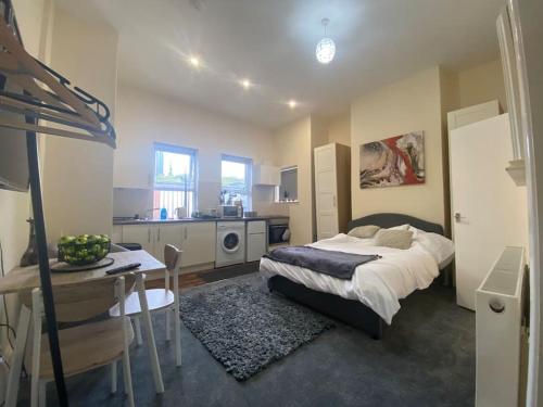 a bedroom with a bed and a table and a kitchen at Modern studio apartment - great location! in Mansfield