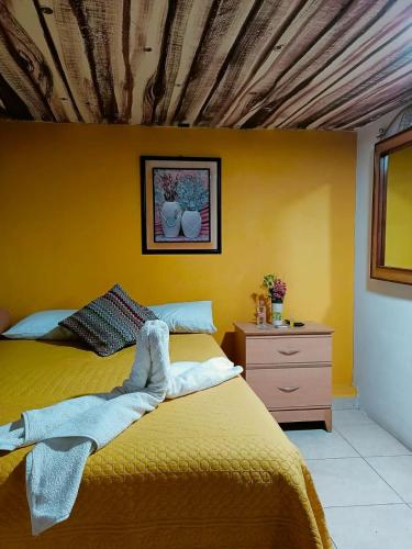 a yellow bedroom with a bed and a dresser at Villa Victoria Pirámides in San Martín de las Pirámides
