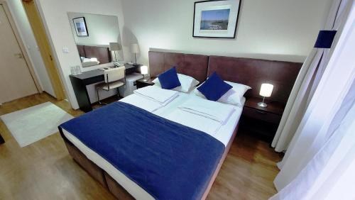 a bedroom with a bed with blue sheets and a mirror at Hotel Villa Panorama in Belgrade