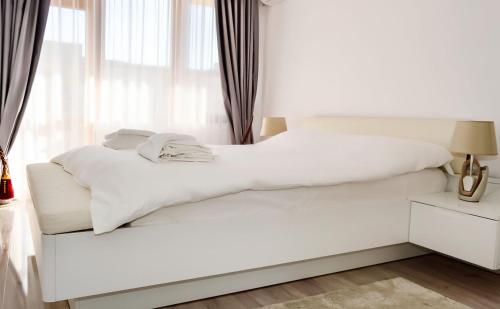 a white bed in a room with a window at Lighthouse Golf Resort, 75 mp2, with balcony in Balchik