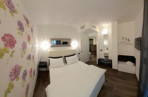 Montiano的住宿－Ca Bianca，卧室配有白色的床铺,墙上挂着鲜花