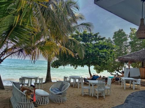 a beach with chairs and tables and the ocean at Twice Happy Beach Garden in Tangalle