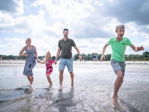 eine Familie spielt im Wasser am Strand in der Unterkunft Landal Travemnde in Travemünde