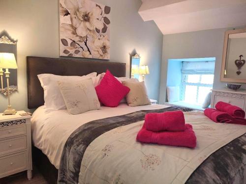 a bedroom with a large bed with red pillows at Woodside Cottage with free Spa access in Newby Bridge