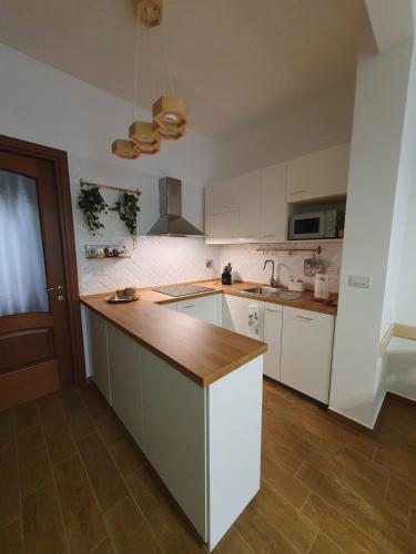 a kitchen with white cabinets and a wooden counter top at Casa eNNe, Appartamento Vicino Centro e Juventus Stadium in Turin