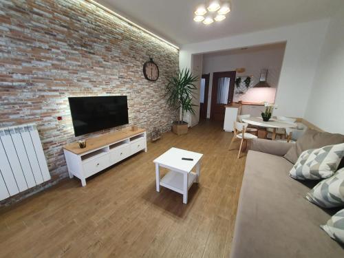 a living room with a brick wall and a flat screen tv at Casa eNNe, Appartamento Vicino Centro e Juventus Stadium in Turin