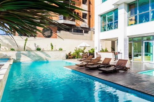 MANDAI Apartamento Cabo Frio في كابو فريو: مسبح مع كراسي جلوس بجانب مبنى