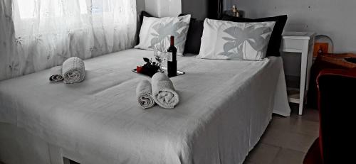 un letto bianco con tavolo, asciugamani e bottiglie di vino di Asterakia a Spiaggia di Aliko