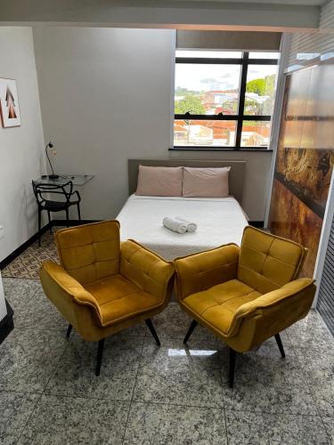 a small bedroom with a bed and two chairs at Apart Hotel Seg Total Lofts Encantadores in Mogi-Guaçu