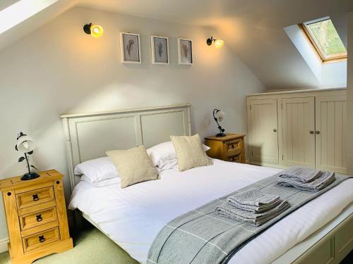 - une chambre avec un grand lit blanc et 2 tables de chevet dans l'établissement Stable Cottage, à Corwen