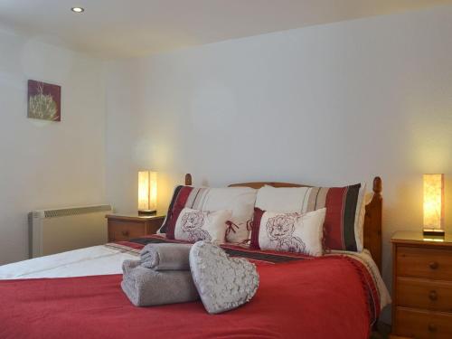 a bedroom with a bed with red sheets and pillows at Bridgend Cottage in Lostwithiel