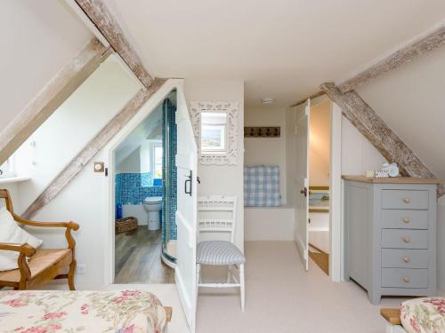 a small attic bedroom with white walls and wooden beams at Sweet Pea Cottage in Kingston