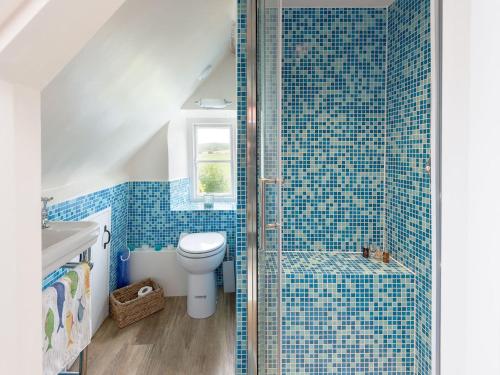 a bathroom with a toilet and a shower with blue tiles at Sweet Pea Cottage in Kingston