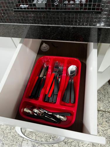a red tray with utensils in a drawer at Apart Hotel Seg Total Lofts Encantadores in Mogi-Guaçu