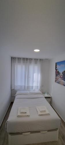 Habitación blanca con cama y ventana en APTO TANEZ SAN FRANCISCO STYLE, a en Madrid