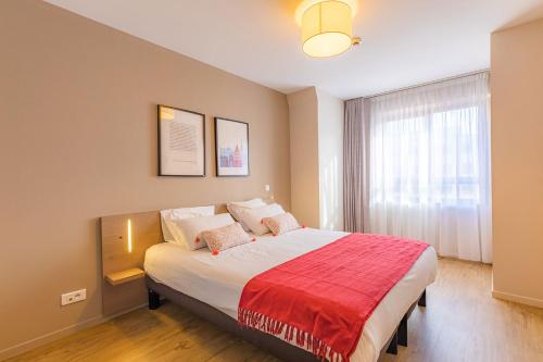 - une chambre avec un grand lit et une couverture rouge dans l'établissement Appart'City Confort Strasbourg Centre, à Strasbourg