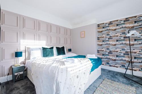 a bedroom with a white bed and a brick wall at Stylish 3 Bedroom Townhouse close to Chester City Centre - Ideal for Families, Groups and Contractors in Hough Green