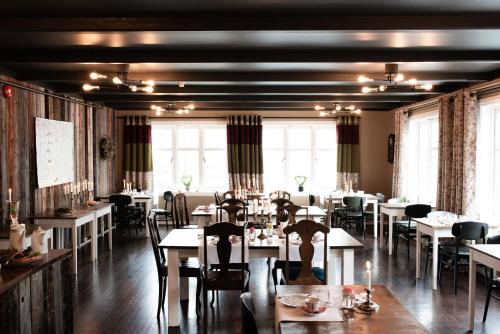 un comedor con mesas, sillas y ventanas en Fjærland Fjordstove Hotell - Huseby Hotelldrift AS, en Fjærland
