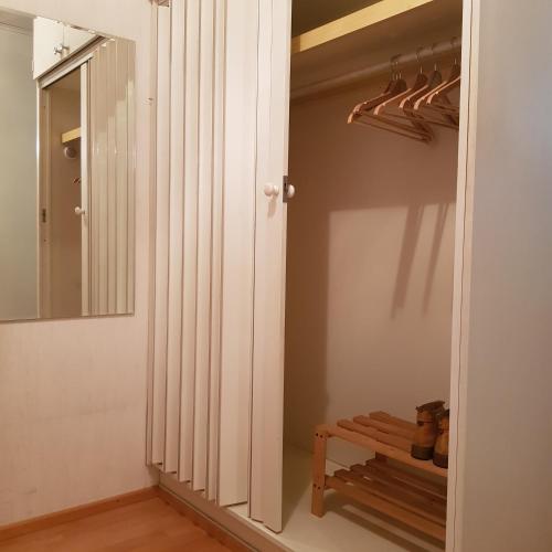 a closet with a mirror and a wooden bench at Tilava kolmio keskustassa in Ylivieska