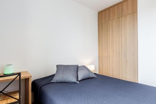 um quarto com uma cama azul e um armário de madeira em Bright Apartment with Balconies em Barcelona