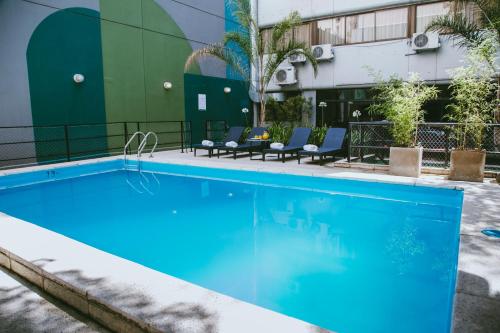 uma piscina num hotel com cadeiras e um edifício em Deco Collection em Buenos Aires