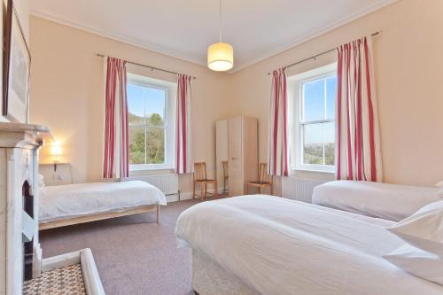 a bedroom with two beds and two windows at The Presbytery Coniston in Coniston