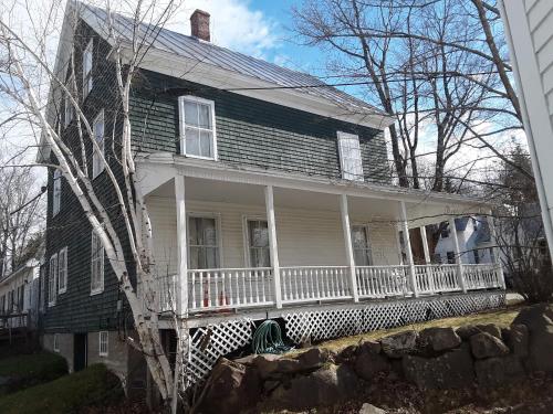 an old house with a large white porch with a porch at Terrapin Hostel in Kingfield