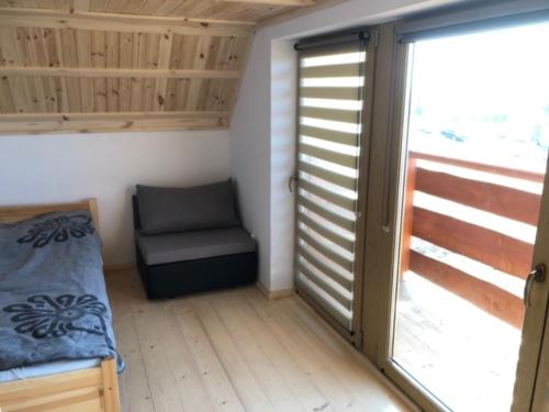 a room with a bed and a chair and a sliding door at DOM u WIECHA in Huba