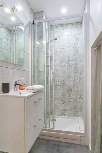 une salle de bain blanche avec une douche et un lavabo dans l'établissement Le Bossuet en plein coeur du centre historique, à Dijon