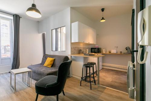 Una sala de estar con una silla y una cocina. en Le Bossuet en plein coeur du centre historique, en Dijon