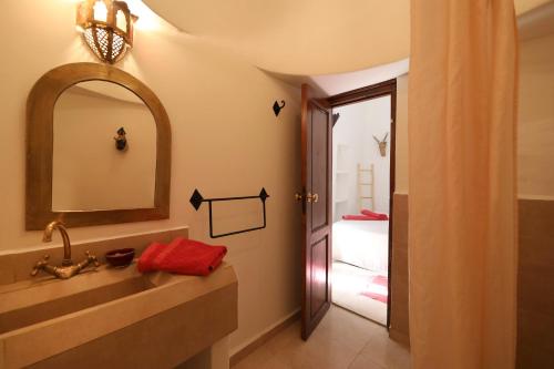 a bathroom with a sink and a mirror and a bed at Riad Noor Charana in Marrakesh