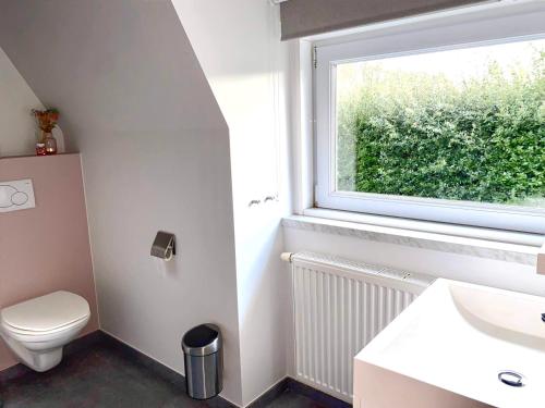 baño con aseo y lavabo y ventana en Vakantievilla 3 Beaufort, en Nieuwpoort