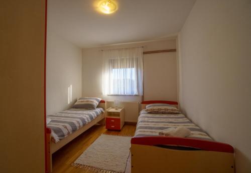 three beds in a room with a window at Apartment Vanessa in Gospić