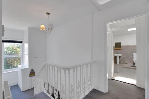 a white staircase in a white room with a window at Hamilton Apartments hosted by Maysa London in London